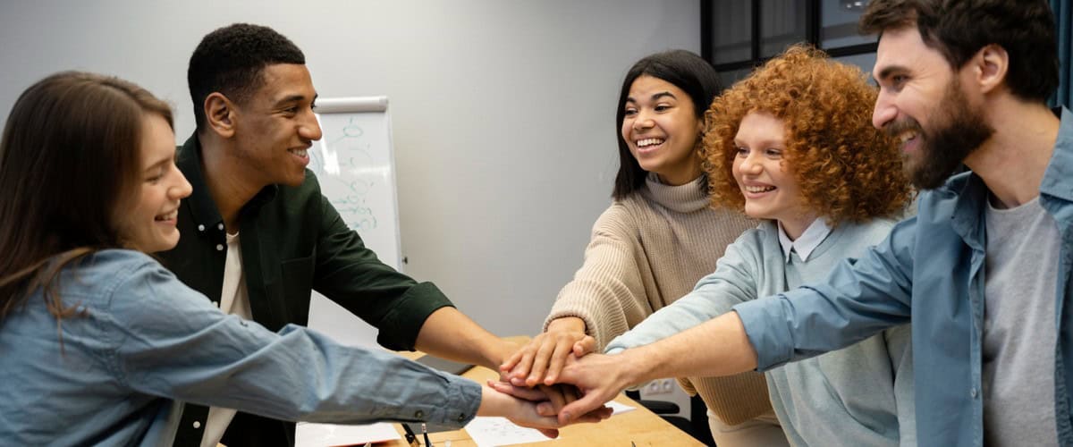 cultura organizacional - equipe em volta da mesa de trabalho com as mãos unidas no centro