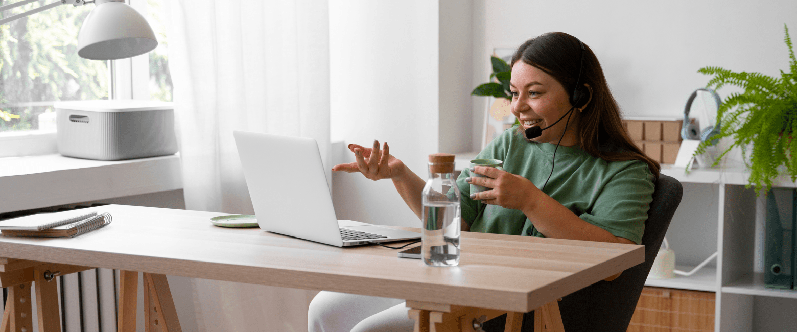 mulher com xícara na mão e fone de ouvido na frente do computador indicando bem-estar no trabalho híbrido