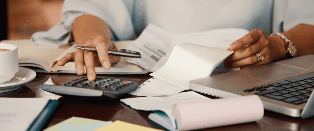 uma mulher com calculadora e papéis na mão para calcular taxa de ocupação do escritório