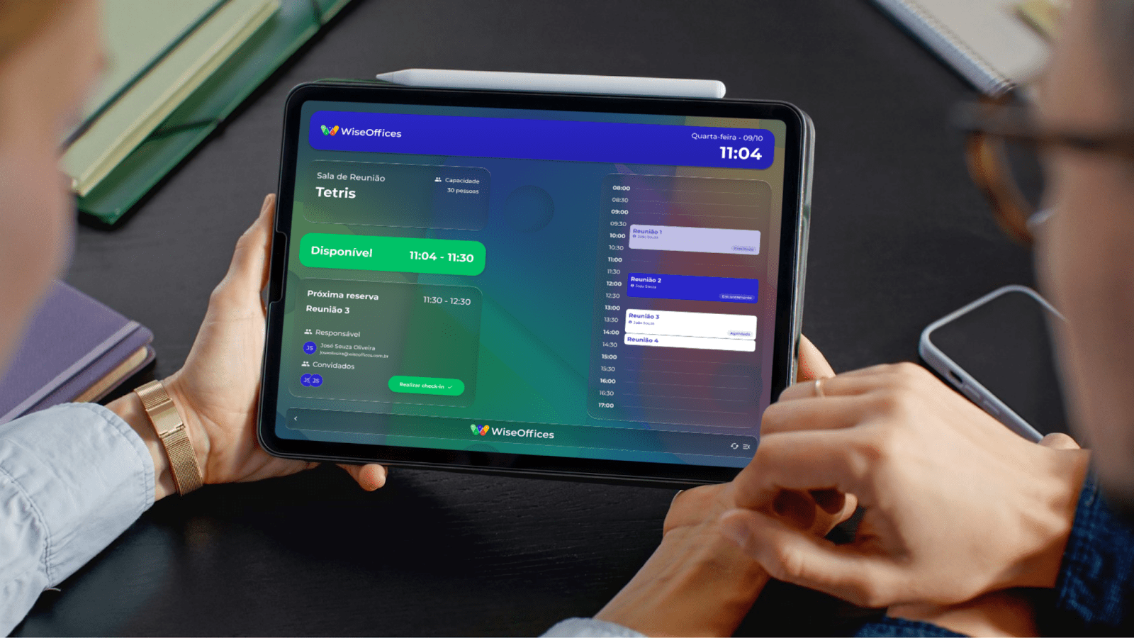 Tablet exibindo interface de sinalização digital para gestão de espaços em escritório, com informações sobre disponibilidade e agendamentos.